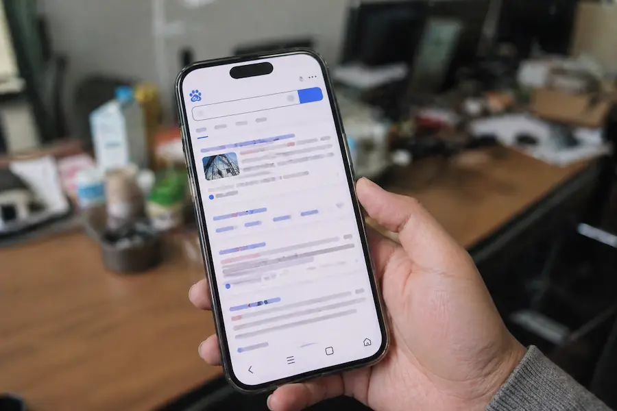 益阳实体店内，老周手持手机展示某企业网站在百度搜索结果里的靠前位置